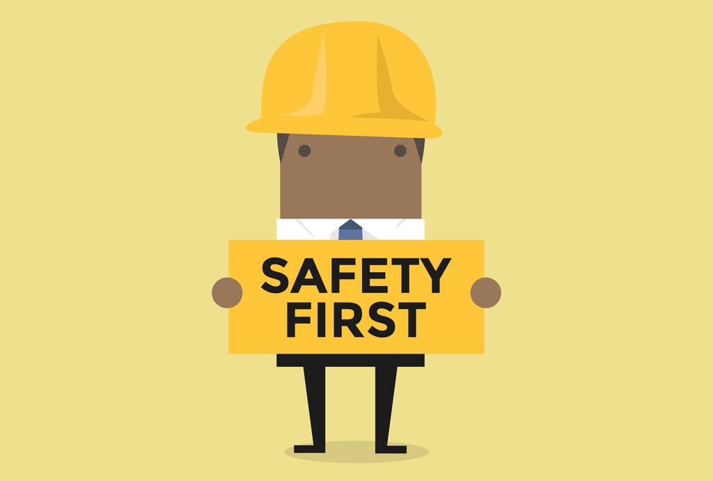 Cartoon character in a hard hat holding a placard which reads 