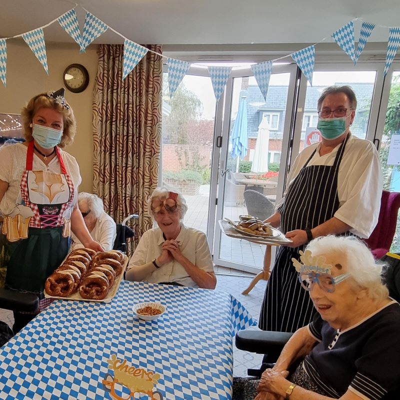 Companionship team member and native German speaker Christina Holliday and Chef Chris Warren serve freshly baked pretzels (Brezel in German) to Kingfishers residents June Price, seated centre, and Joan Graves