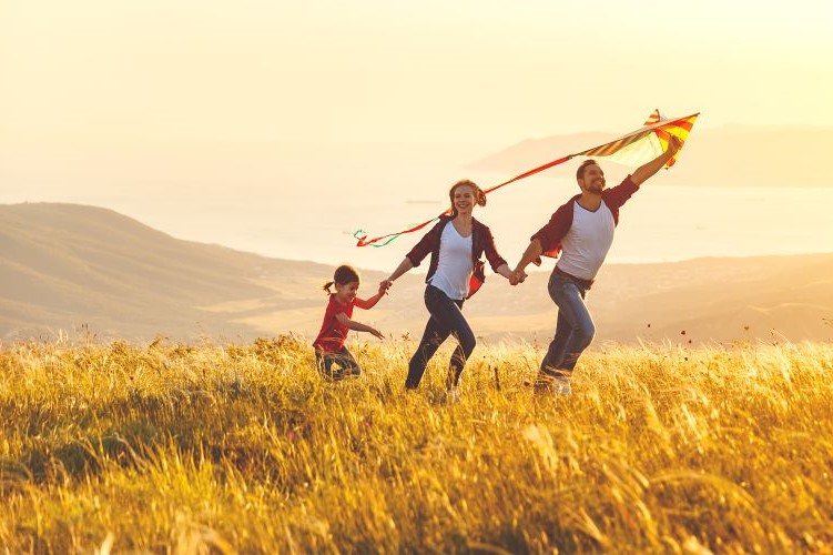 couple with child on hill top flying kite